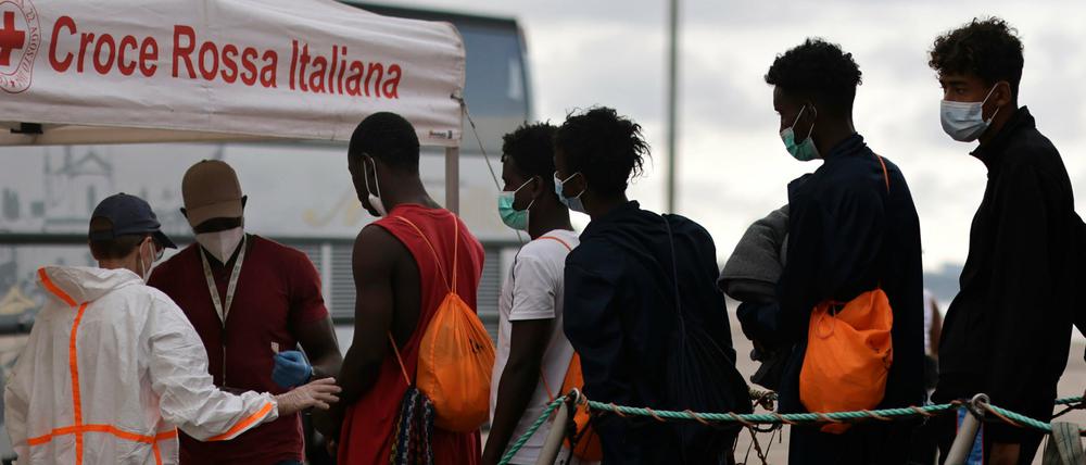 Migranten gehen von Bord der „Ocean Viking“ und werden von Mitgliedern des italienischen Roten Kreuz im Hafen von Taranto in Empfang genommen.