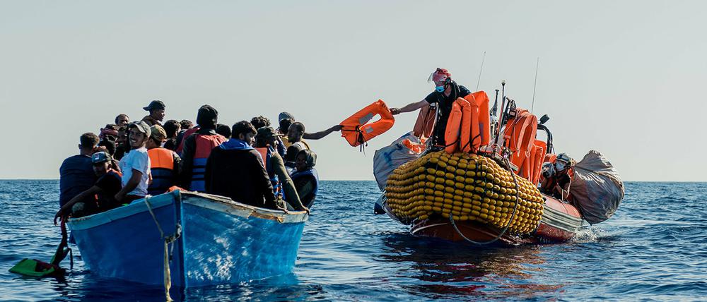 Hilfskräfte nähern sich einem Boot mit Migranten auf dem Mittelmeer.