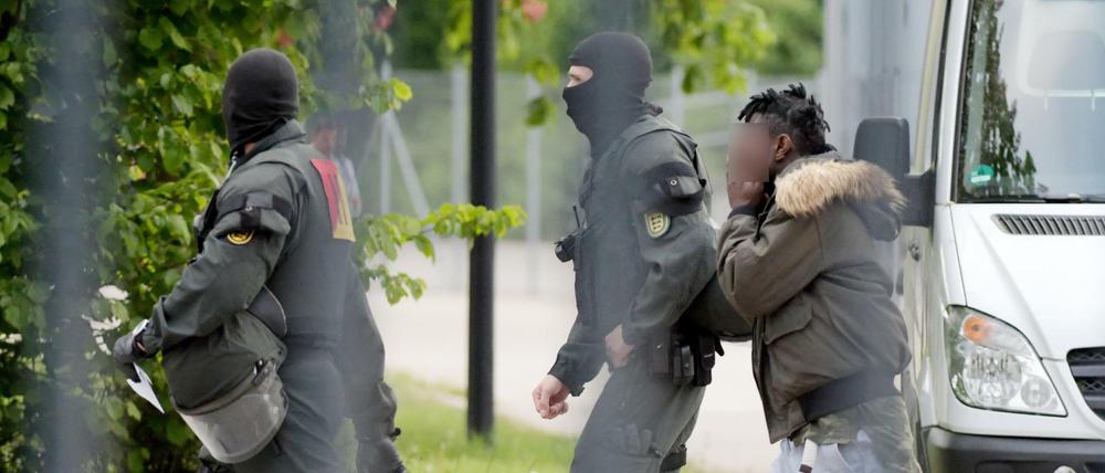 Ein Mann in Ellwangen wird von maskierten Polizisten eskortiert