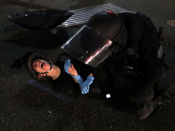Eine Demonstrantin wird von einem Polizisten in Portland auf den Boden gedrückt.