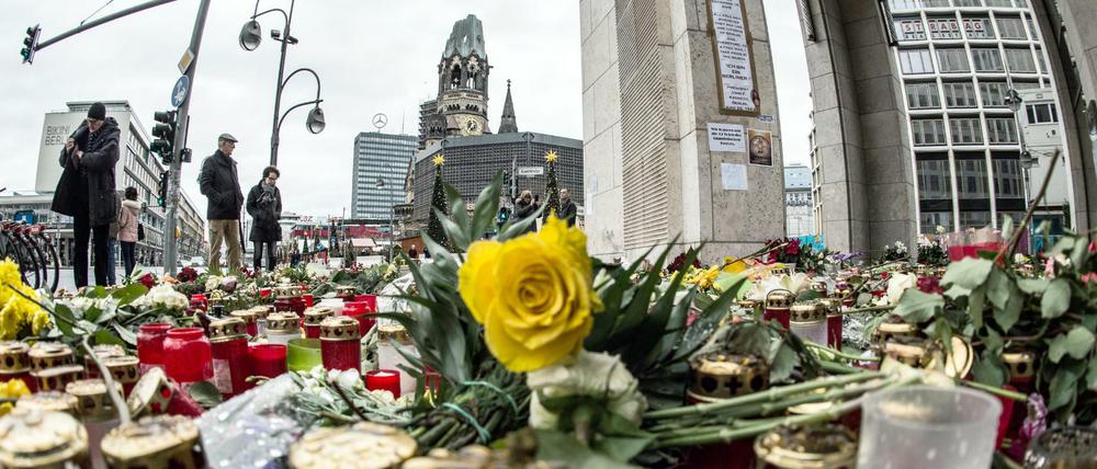 Passanten stehen am 26.12.2016 in Berlin vor einem Blumen- und Kerzenmeer am Breitscheidplatz, dem Ort des Anschlags. 