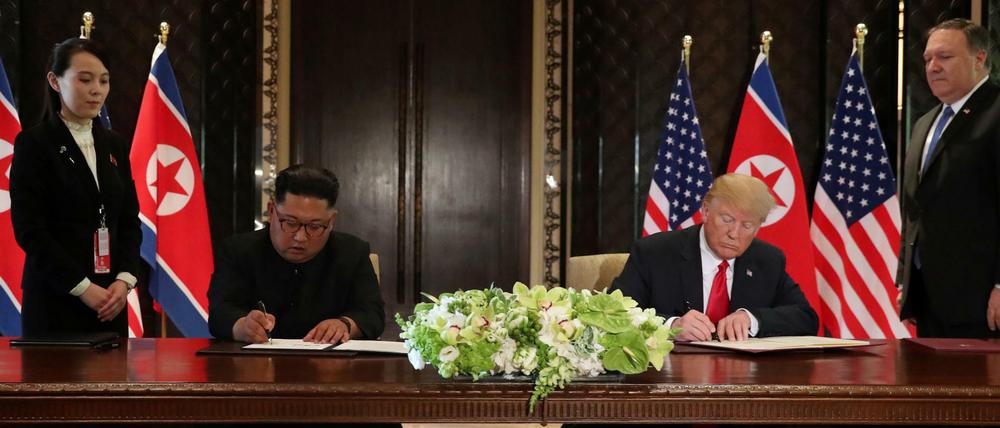 Nordkoreas Machthaber Kim Jong Un und US-Präsident Donald Trump unterzeichnen gemeinsam ein Dokument.