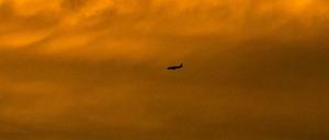 Romantisch. Ein Passagierflugzeug ist im Anflug auf den Flughafen Basel-Mulhouse als Silhouette vor dem vom Sonnenuntergang gefärbten Himmel zu sehen. 