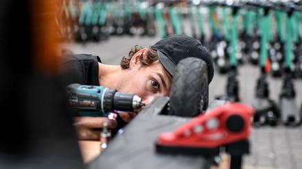Florian Väth, Mechaniker baut ein Rad an einem E-Tretroller des Anbieters Tier an.