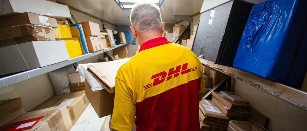 Ein Mitarbeiter des Unternehmens Deutsche Post DHL belädt sein Auto.