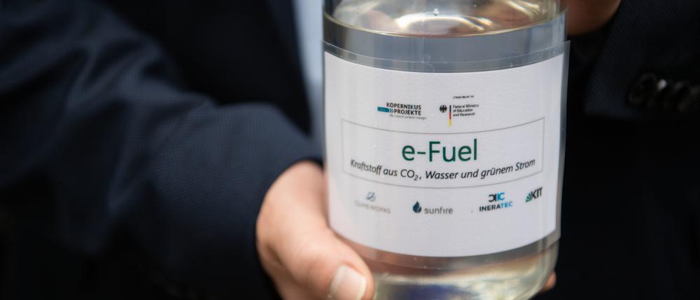 Ein Besucher hält eine Flasche mit E-Fuel aus einer Forschungsanlage des Karlsruher Instituts für Technologie (KIT) in den Händen.