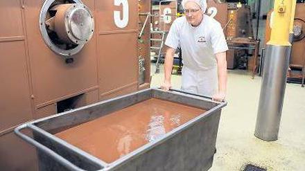 Tonnenweise feine Speise. Ein Mitarbeiter des Bremer „Chocolatiers“ Hachez schiebt eine Wanne geschmolzener Schokolade durchs Werk, das der Investor erhalten will. Foto: dpa
