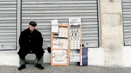 Die Hoffnung stirbt zuletzt. Ein Losverkäufer sitzt in Athen vor einer geschlossenen Bank. 