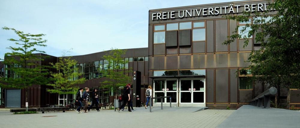 Studierende gehen auf dem Vorplatz des Hauptgebäudes der Freien Universität Berlin auf einen Eingang zu.