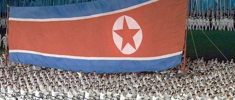 Hunderte nordkoreanische Gymnastik-Schüler marschieren mit einer gigantischen Nordkorea Flagge durch eine Turnhalle