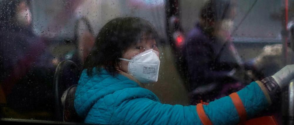 Eine Frau in einem Bus in Shanghai trägt eine Gesichtsmaske.