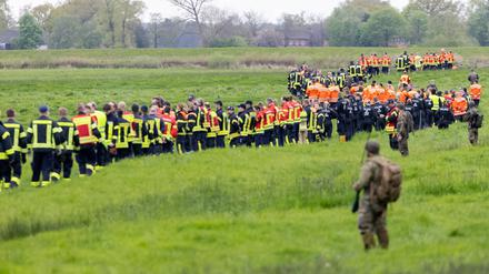 Soldaten der Bundeswehr und Einsatzkräfte von Feuerwehr und Polizei stellen sich auf, um ein Feld abzusuchen. 
