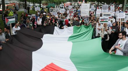 Demonstranten tragen bei der anti-israelischen Demonstration anlässlich des Al-Quds-Tages in Berlin die Flagge Palästinas.