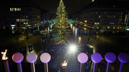 Europas größter Chanukka-Leuchter steht im Gegenlicht eines Scheinwerfers vor dem traditionellen Weihnachtsbaum auf dem Pariser Platz.