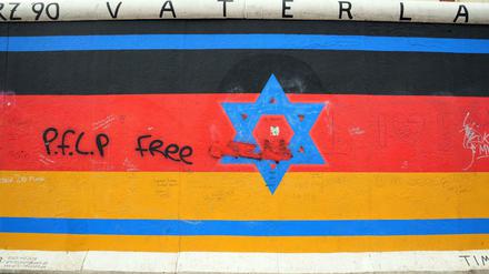 Die einzelnen von Künstlern aus der ganzen Welt bemalten Mauerstücke der East Side Gallery in Berlin - mit aufgesprühtem PFLP-Grafitti. 