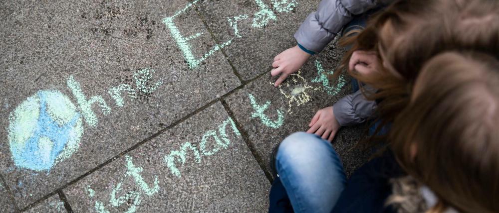 Zwei Mädchen schreiben bei der Klima-Kundgebung "Fridays for Future" am Invalidenpark den Satz "Ohne Erde ist man tot".