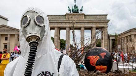 Ein Aktivist von Extinction Rebellion trägt zum "Global Earth Overshoot Day" vor dem Brandeburger Tor eine Gasmaske.