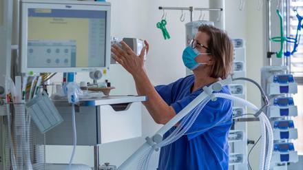 Eine Krankenschwester prüft ein Beatmungsgerät in einem Zimmer einer Intensivstation.