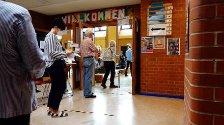 Menschen stehen vor einem Wahllokal in einer Berliner Schule an. 