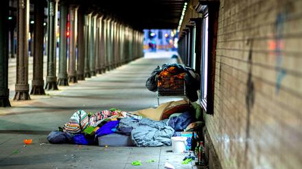 Ein Obdachloser liegt unter einer Bahnunterführung.