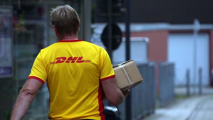 Ein Paketzustellerder von Deutsche Post DHL liefert ein Paket aus.