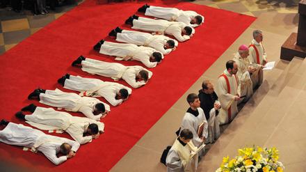 Priesteranwärter liegen während ihrer Weihe zum Priester als Zeichen der Demut bäuchlings auf einem roten Teppich im Freiburger Münster.