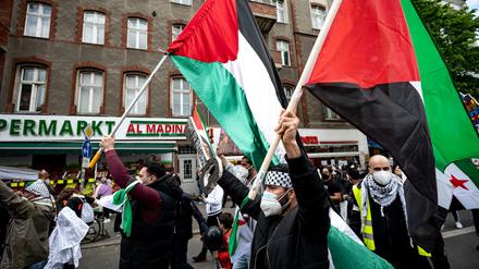 Teilnehmer der Demo verschiedener palästinensischer Gruppen laufen mit Palästina-Flaggen durch Neukölln.