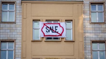 Ein Plakat gegen den Verkauf von Mietwohnungen an die Deutsche Wohnen an einer Fassade in der Karl-Marx-Allee. 