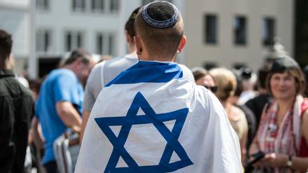 In eine israelische Fahne eingewickelt demonstriert ein Mann im Juli in Bonn gegen Antisemitismus.