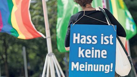 Eine Demonstrantin trägt ein Schild auf dem Rücken, auf dem steht „Hass ist keine Meinung!“. 