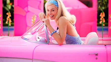 Margot Robbie sitzt als Barbie in einem pinken Cabrio.