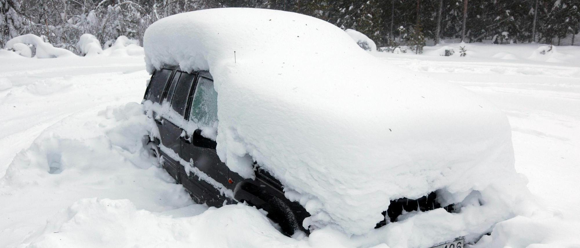 Frau reinigt auto nach einem schneesturm mit einer bürste vom schnee