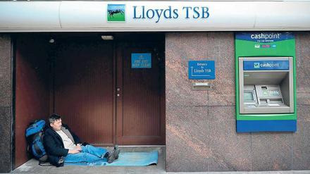 Kreislauf. Eine Obdachloser in London liegt im Eingang der Bank Lloyds TSB, die mit Steuergeldern gerettet werden musste. Die Briten bezahlen die riskanten Bankgeschäfte und Staatsschulden der Vergangenheit mit harter Sparpolitik – fast klaglos. Foto: AFP