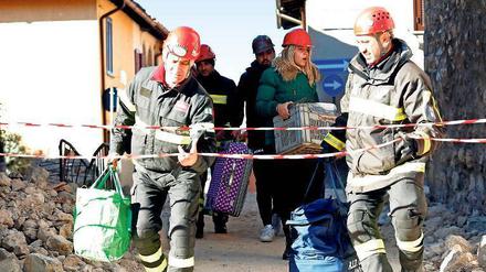 Feuerwehrleute helfen Menschen in Norcia, ihre Habseligkeiten zu retten. 