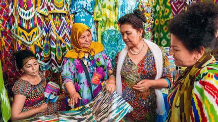 Bunte Seidenstoffe aus Usbekistan werden von Besuchern in Augenschein genommen.
