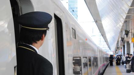 Ein Zugbegleiter schaut aus der Tür eines Hochgeschwindigkeitszugs Shinkansen. 