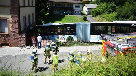 Einsatzkräfte begutachten eine Unfallstelle an der ein Linienbus gegen ein Wohnhaus gefahren ist.