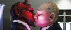 Russlands Präsident Wladimir Putin beim sozialistischen Bruderkuss mit dem Teufel beim Richtfest der Persiflagewagen und Karnevalswagen zum Kölner Rosenmontagszug 2023 in der Koelnmesse.