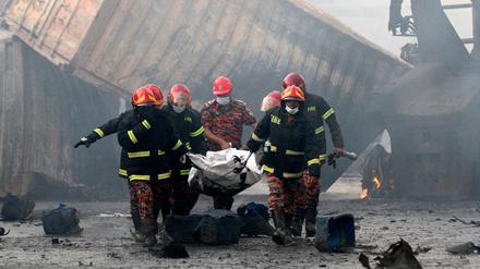 Feuerwehrleute bergen ein Opfer des Brandes in einem Containerlage in Bangladesch. 