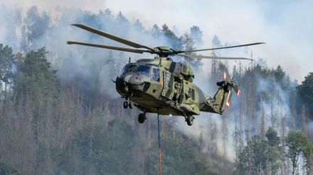 Hubschrauber der Bundeswehr fliegen mit einem Löschwasser-Außenlastbehälter über die Brände im Nationalpark Sächsische Schweiz.
