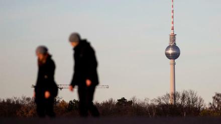 Spaziergänger gehen auf dem Tempelhofer Feld vor dem Berliner Fernsehturm. Statt Schnee ist es in Deutschland grau und trüb. 