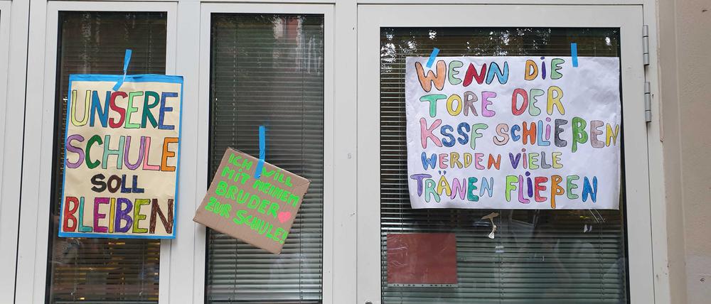 Mit selbst gebastelten Schildern protestieren Schüler und Eltern vor dem Schulgebäude.
