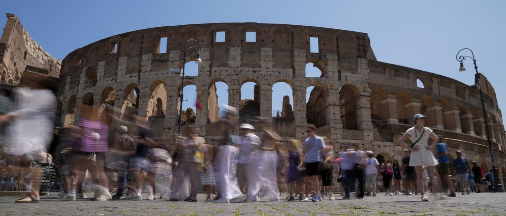 27.06.2023, Italien, Rom: Besucher gehen am Kolosseum in Rom vorbei.