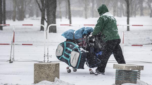 Ein Obdachloser mit einem Einkaufswagen im Berliner Winter.