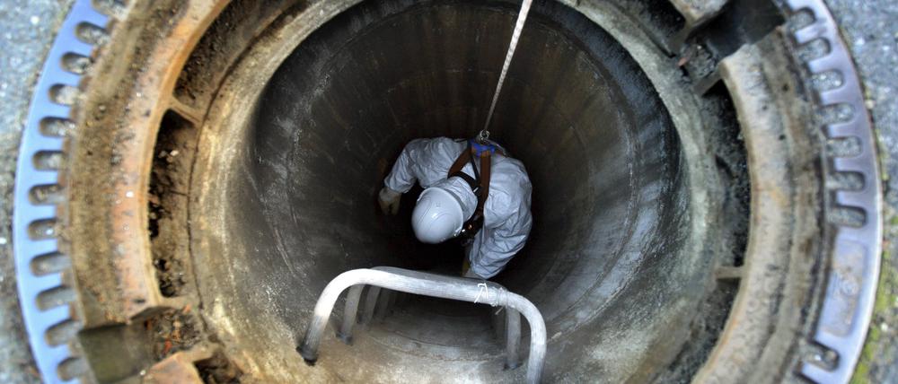 Ein Kanalarbeiter steigt in die Kanalisation, um eine Abwasserleitung zu kontrolliere.