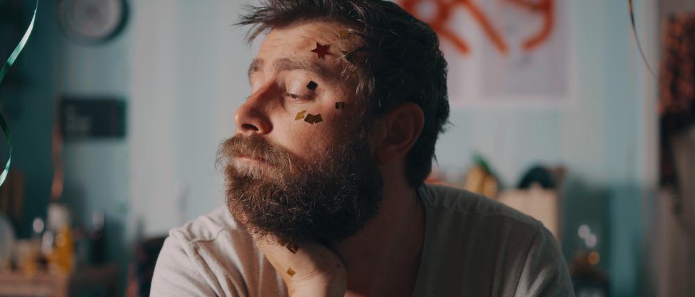 Mann mit Konfetti im Gesicht guckt verknautscht.