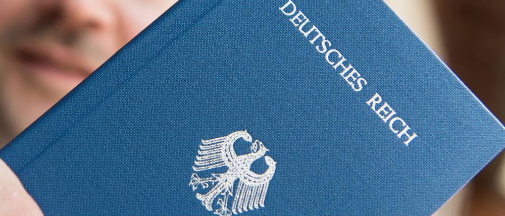 Ein Mann hält ein Heft mit dem Aufdruck «Deutsches Reich Reisepass» in der Hand.