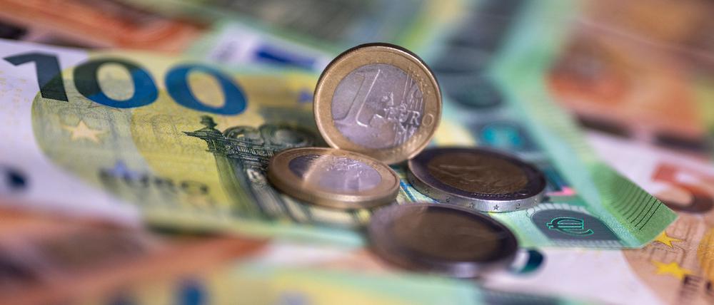 Geldscheine mit dem Wert von 100 und 50 Euro und Münzen liegen auf einem Tisch.