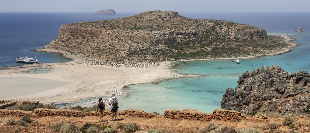 Touristen gehen mit Blick auf den Strand von Balos und seine Lagune im nordöstlichen Teil der Insel Kreta entlang (Symbolbild).