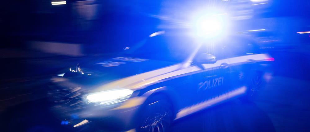 Ein Polizeifahrzeug fährt mit Blaulicht an einem Gebäude vorbei. (Symbolbild)